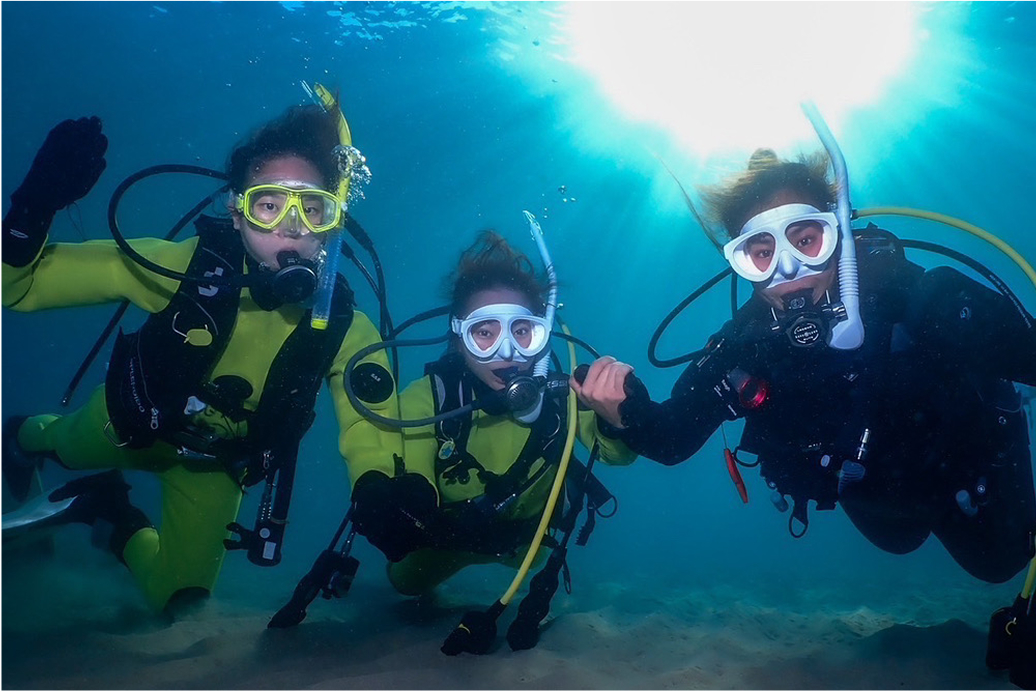 男女のダイバーたちが船に乗って笑いかけている